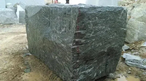 Rough-cut granite block displayed in a collection of natural stone materials.
