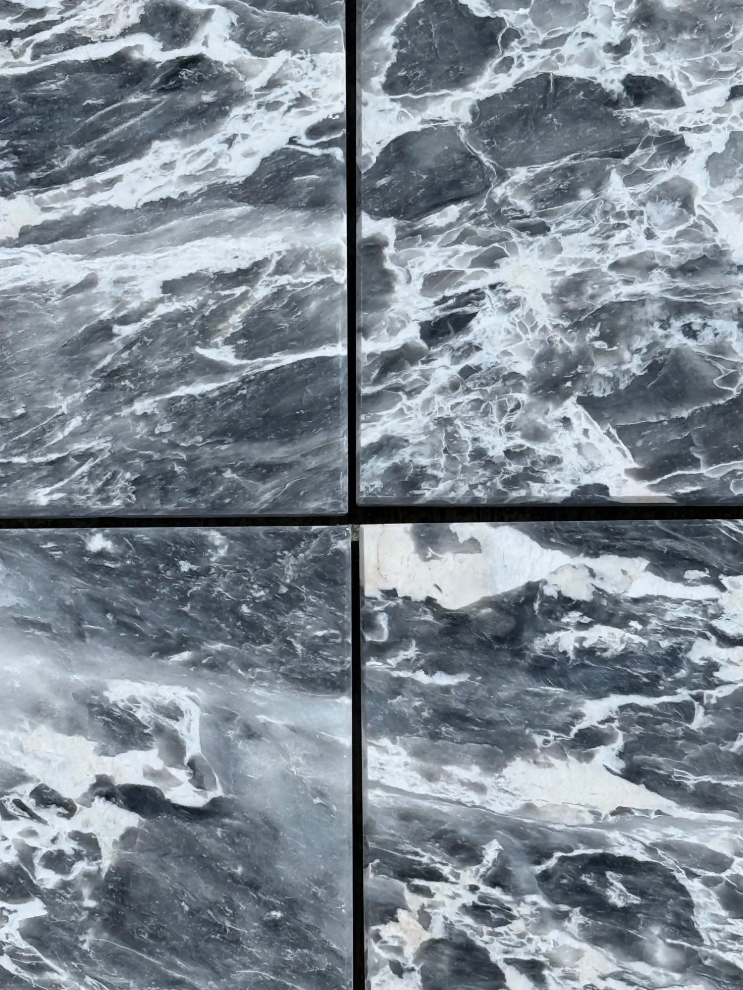Four Storm Gray Marble tiles with dark grey background and prominent white veining