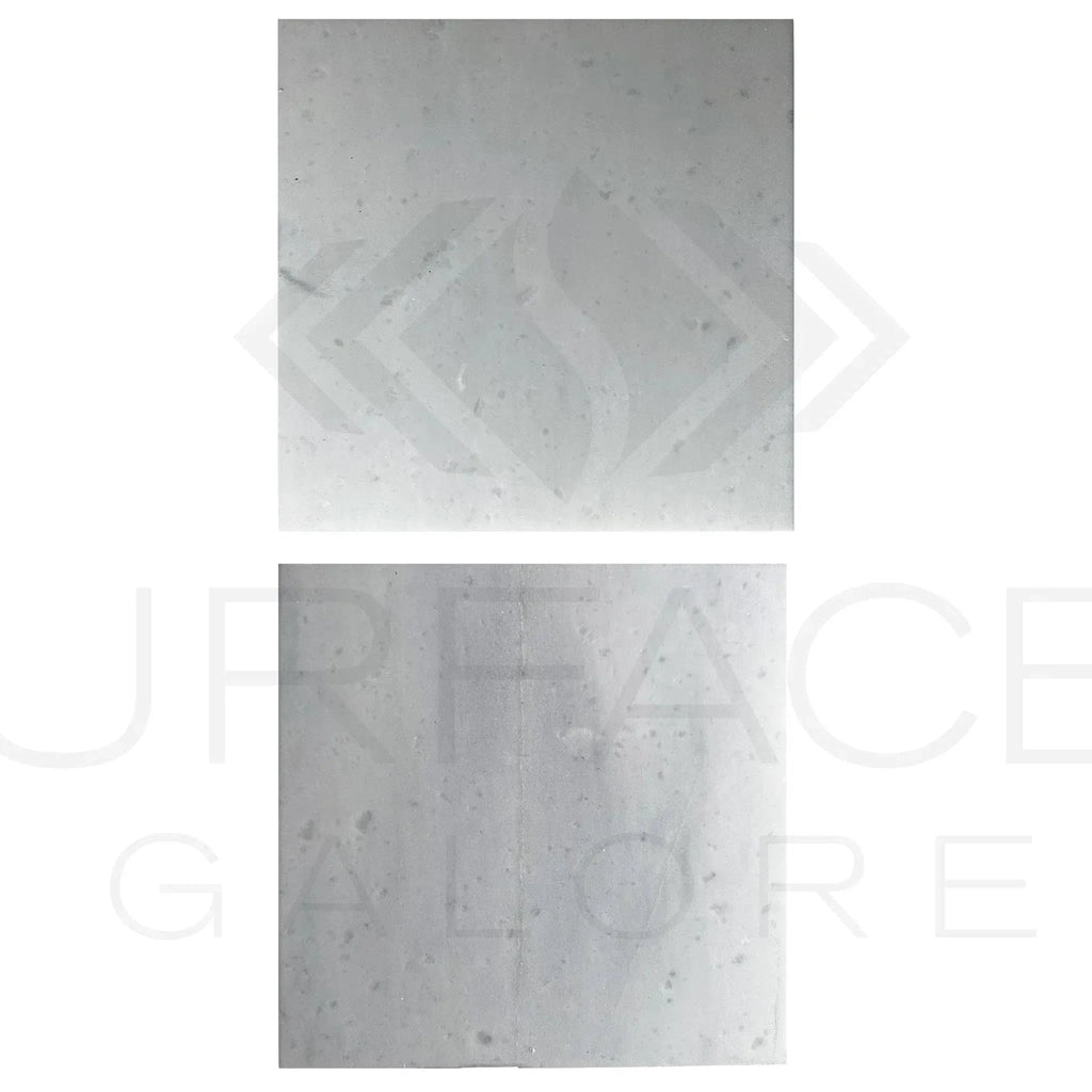 Two square light-colored Agean White Marble tiles, polished and 12X12 inches