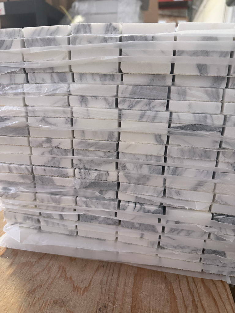 Stack of Arabescato Corchia 12x12 polished marble mosaic tiles in white and gray, wrapped in plastic