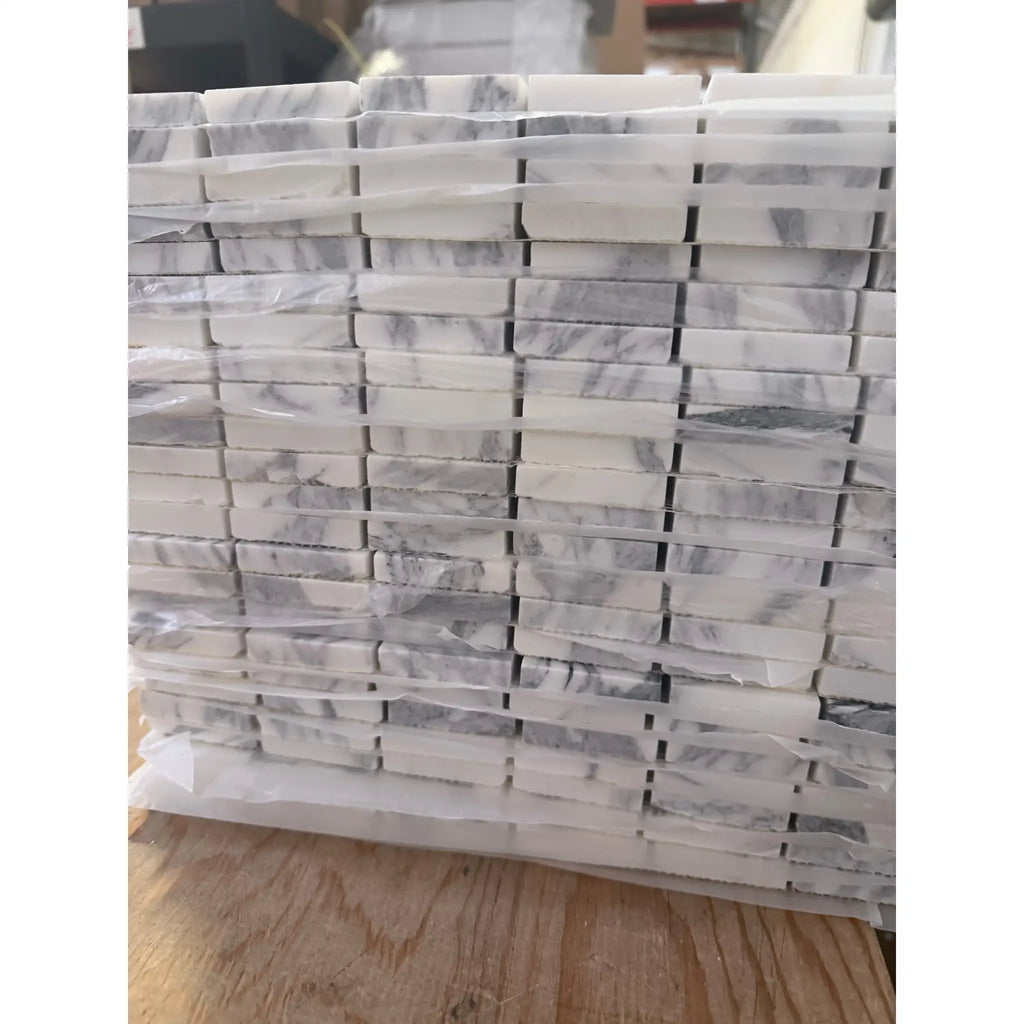Stack of Arabescato Corchia white gray marble mosaic tiles in plastic