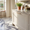 Arabescato corchia 12x24 white marble tile with gray veining on countertop and gold-toned cabinet handle