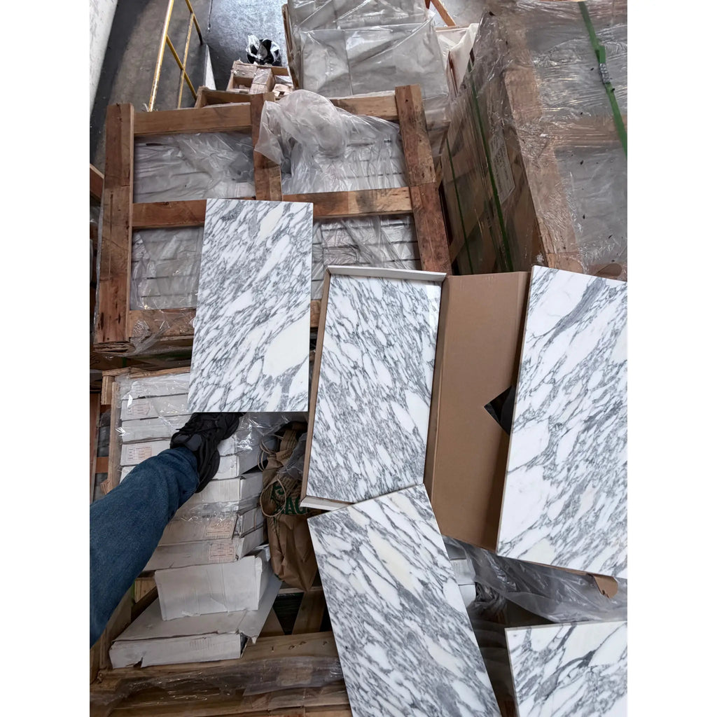 Stacked white and gray veined Arabescato Corchia marble slabs on pallets