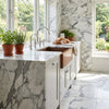 The arabescato corchia 18x18 polished marble tile complements a copper farmhouse sink in a bright kitchen
