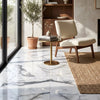 A sleek round side table with a polished gold metal base and reflective Arabescato Corchia marble top