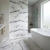 White freestanding bathtub with modern curves and polished chrome faucet on arabescato corchia 24x24 marble tile polished