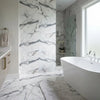 White freestanding bathtub with sleek modern curves paired with polished or honed Arabescato Corchia 24x24 marble tile
