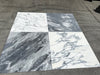Four large Arabescato Corchia 24x24 marble tiles in subtle white veining and dramatic dark gray streaks