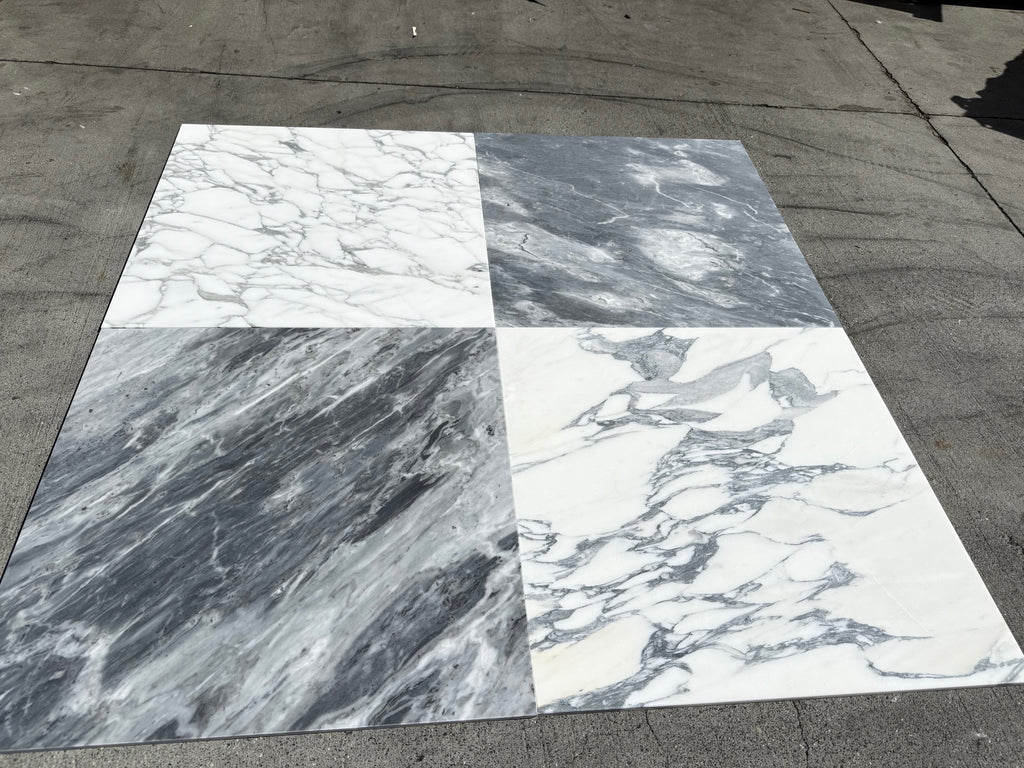 Four large Arabescato Corchia 24x24 marble tiles in subtle white veining and dramatic dark gray streaks