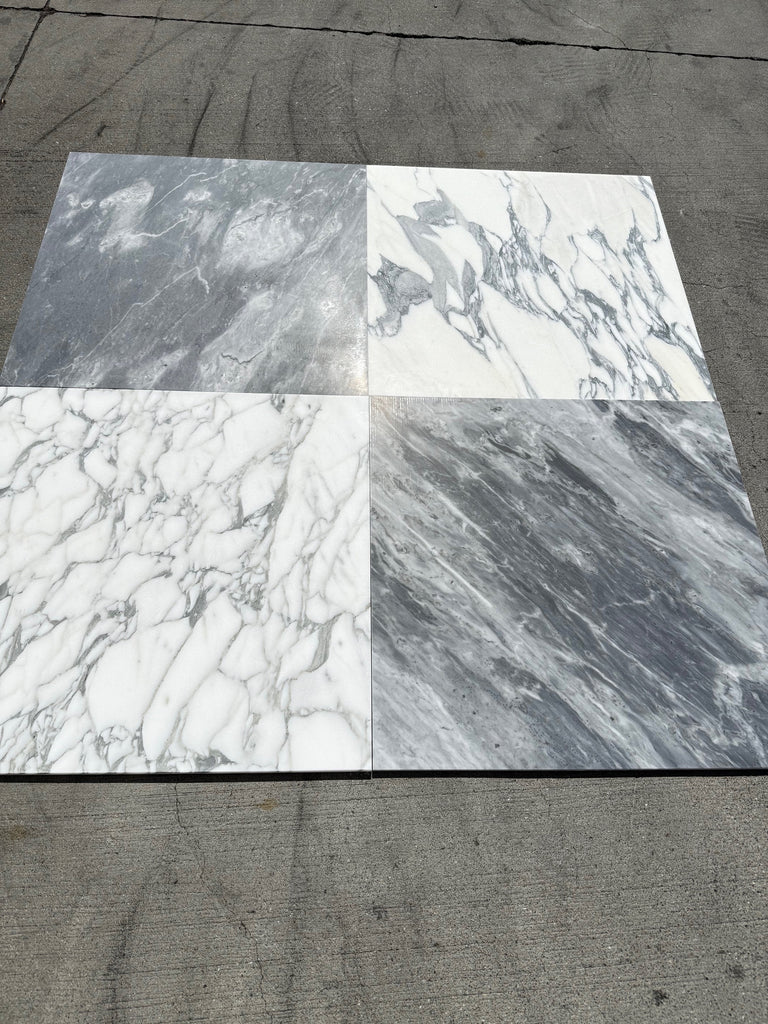Four marble-like square tiles featuring Arabescato Corchia patterns in white and gray finishes