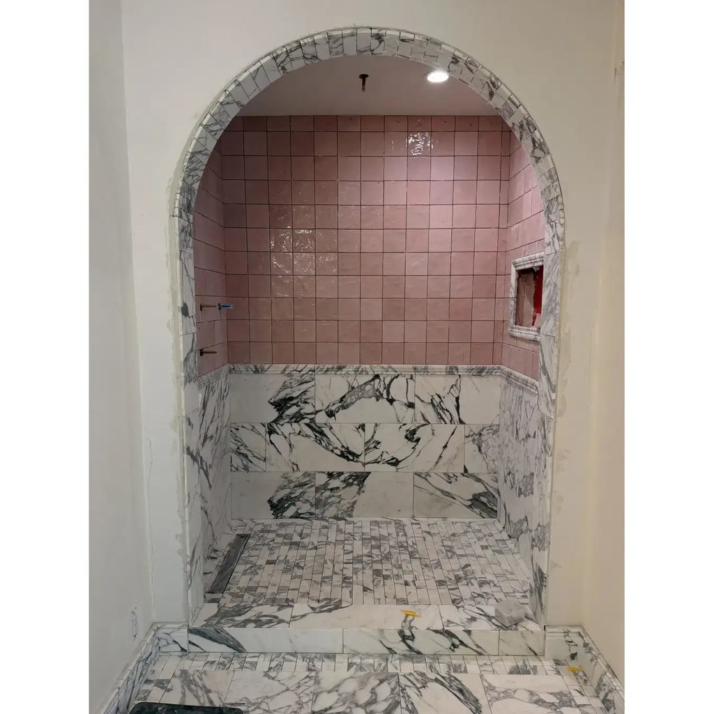 Arabescato Corchia marble mosaic shower with pink and white marble tiles and a curved archway design
