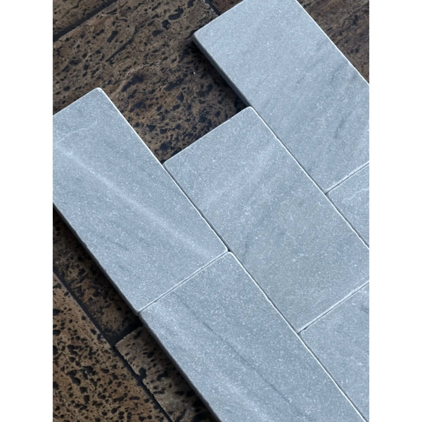 Gray rectangular bardiglio imperiale 3x6 marble tumbled stone tiles arranged in a herringbone pattern