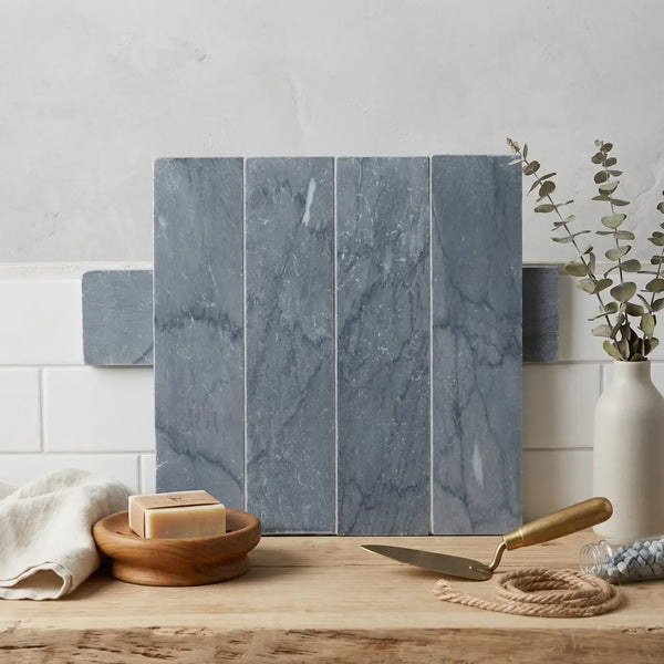 Bardiglio imperiale marble 3 x 12 field tile with blue gray subway tiles featuring subtle veining arranged vertically