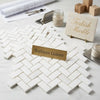 White rectangular bianco dolomite marble tiles arranged in a polished or honed herringbone mosaic pattern