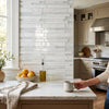 A beige ceramic mug with speckled texture and handle resting on a white dolomite manhattan random-strip mosaic marble countertop