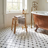 Antique copper clawfoot bathtub with white porcelain interior and ornate brass fixtures in bianco dolomite black mosaic marble