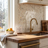 Gold-toned kitchen faucet with sleek curved spout and pull-down spray head paired with calacatta gold diamond marble tile
