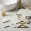 White marble mosaic tiles arranged in a polished calacatta gold 1x4 herringbone pattern for elegant surfaces