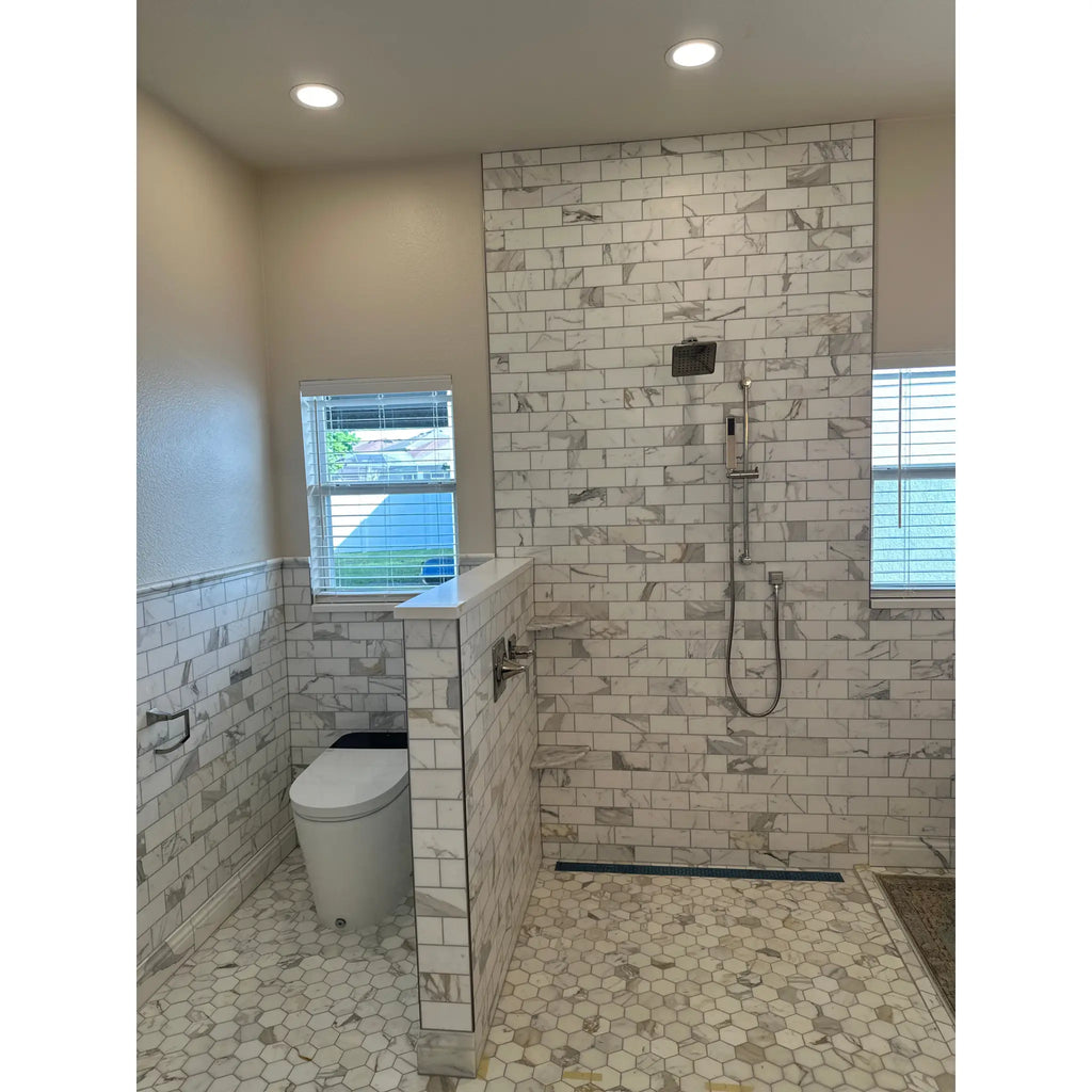 White marble subway tile shower wall with gray veining and matching calacatta gold 2 inch hexagon mosaic marble floor tiles polished or honed