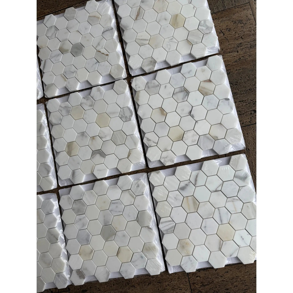 White marble 2 inch hexagon mosaic tiles with subtle gray veining packaged in clear plastic for polished or honed use