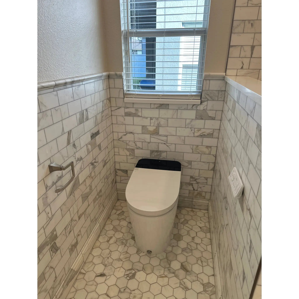 White toilet with black lid in bathroom featuring calacatta gold 2 inch hexagon mosaic marble tile polished or honed