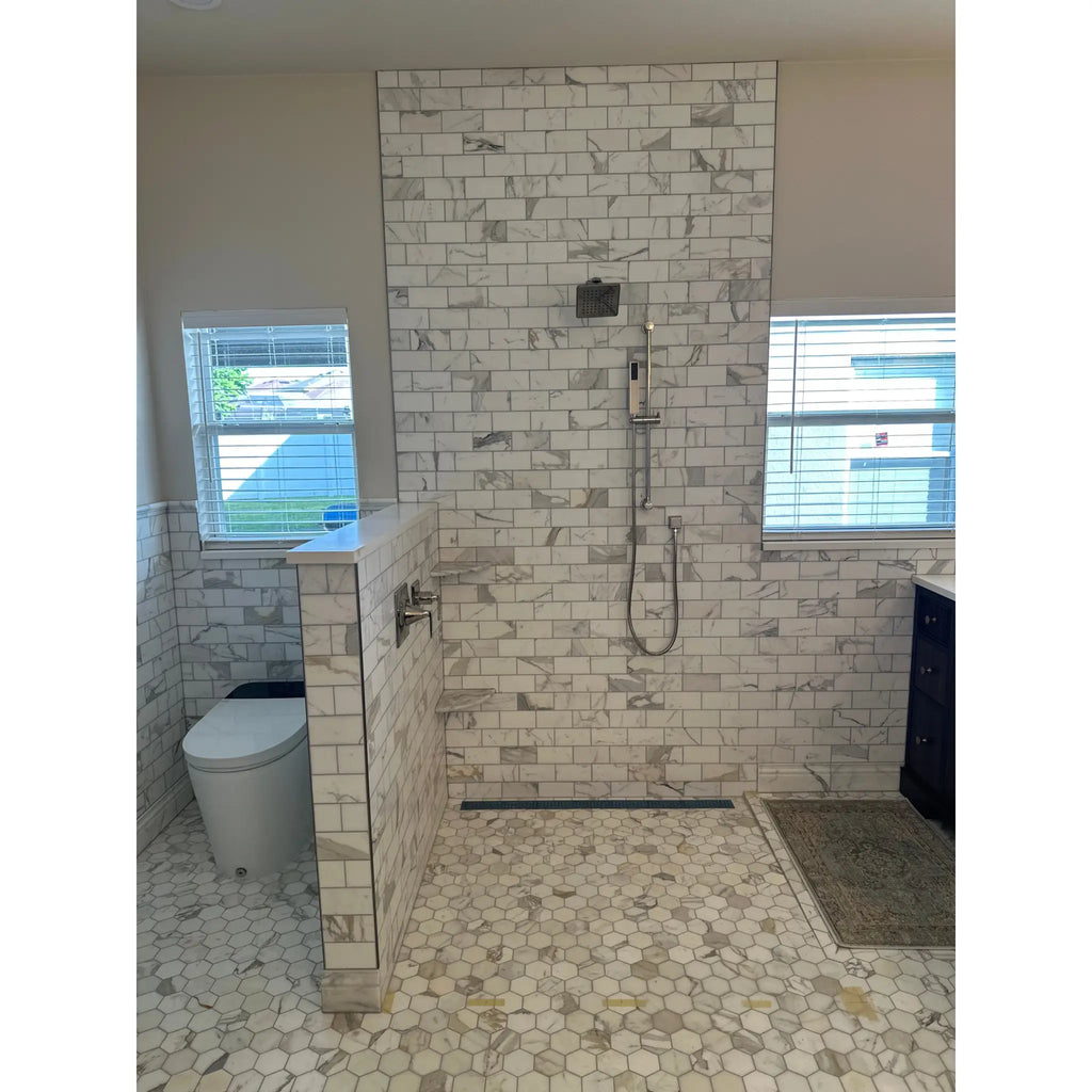 White marble subway tile shower wall with chrome showerhead featuring calacatta gold 2 inch hexagon mosaic tile polished