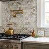 Brass teapot with wooden handle on stovetop beside polished honed Calacatta gold 2x4 deep beveled brick mosaic marble tile