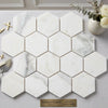 White hexagonal calacatta gold 3 inch polished marble tiles with subtle gray veining in a modern mosaic pattern