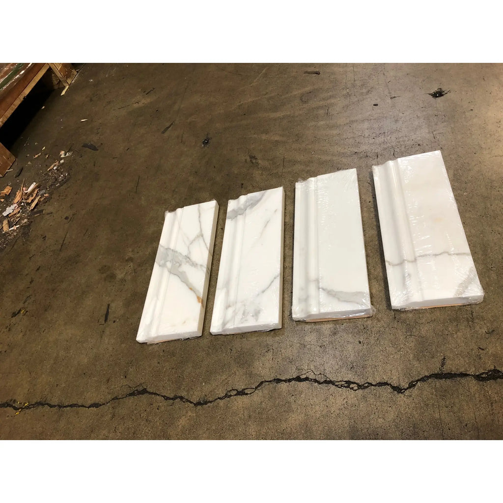 Four white marble calacatta gold baseboard trim moldings with gray veining wrapped in clear plastic for polished or honed finish