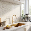 Gold-toned faucet with a sleek curved spout and polished finish paired with calacatta gold 5/8x5/8 mosaic marble tile