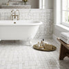 White clawfoot bathtub with gold-toned faucet and ornate feet next to polished calacatta gold basketweave mosaic tile
