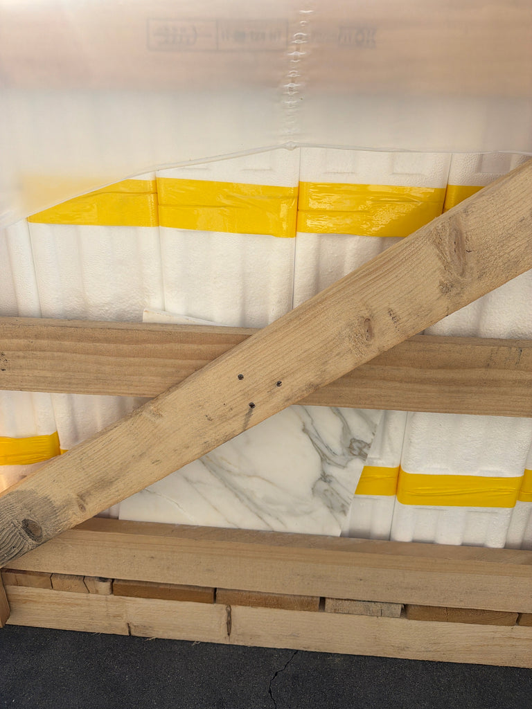 Back of Calacatta Gold Marble 12x12 on wooden pallet with weathered planks