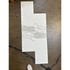 White and gray marble-look tile samples on dark floor for Calacatta Gold Marble 12X24 product