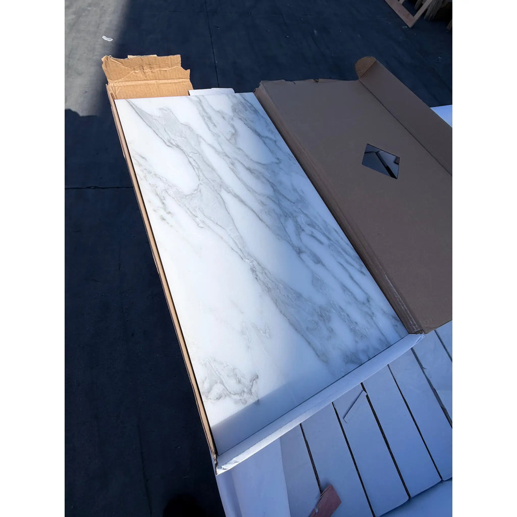 Calacatta Gold Marble 12x24 polished tile with white marble pattern and gray veining, partially unboxed
