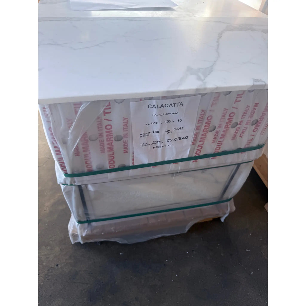Bundle of Calacatta Gold Marble 12x24 tiles with grey veining secured with green straps