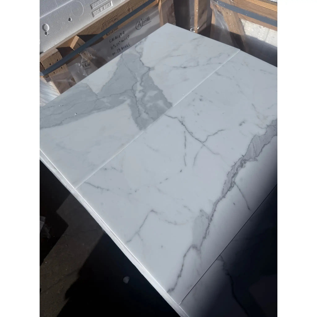 Two large Calacatta Gold Marble tiles with prominent grey veining in polished or honed finish