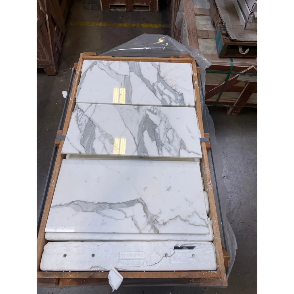 White marble-look tiles with grey veining and golden accents in Calacatta Gold Marble 12X24