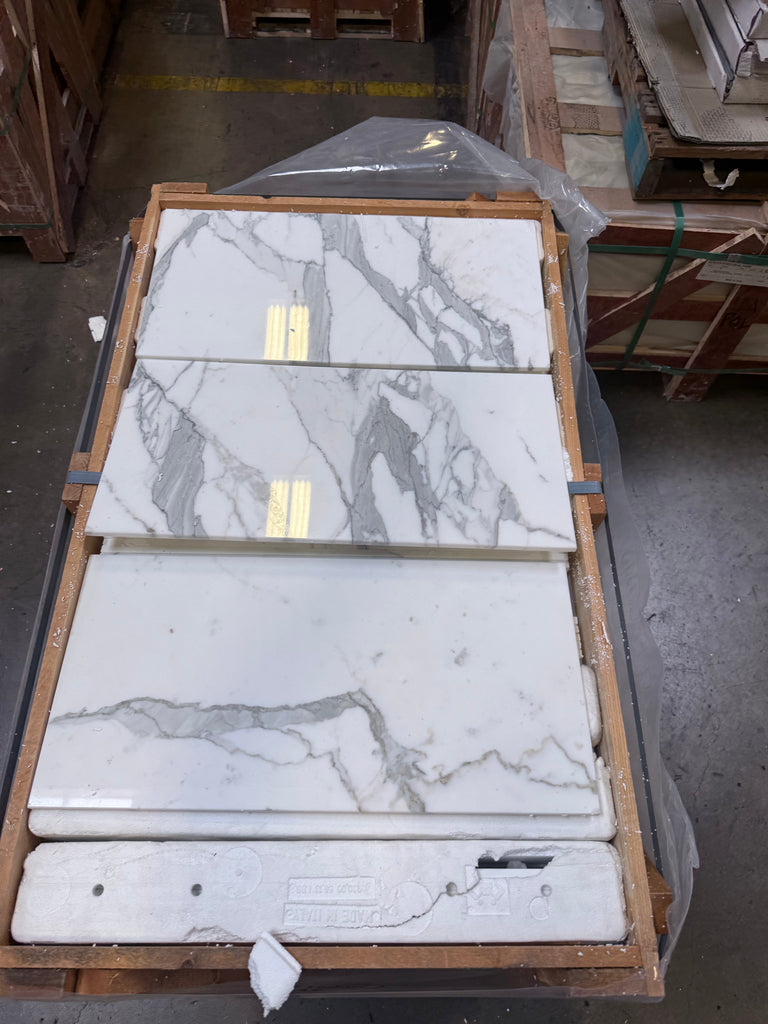 White marble-look tiles with grey veining and golden accents in Calacatta Gold Marble 12X24