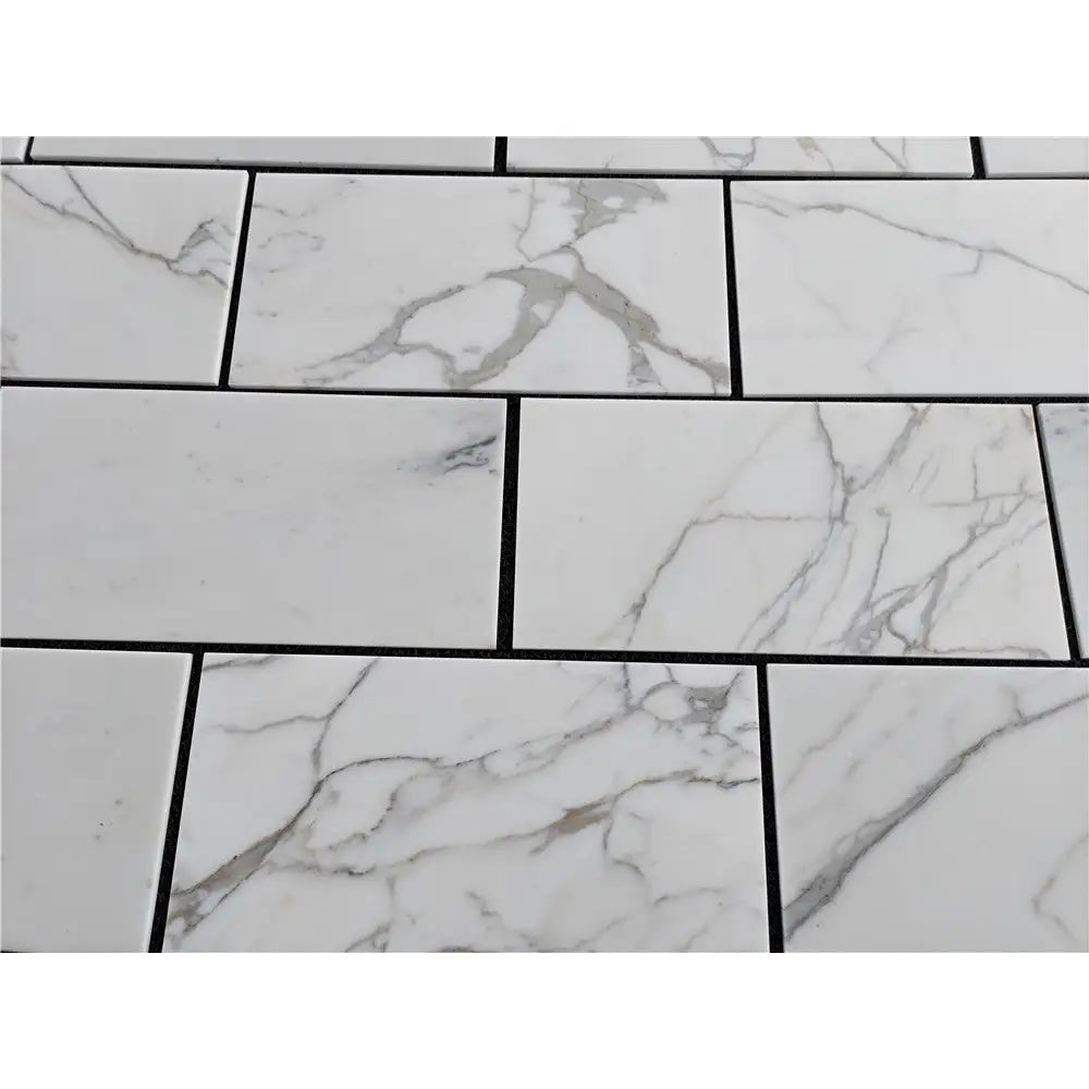 White marble-patterned tiles with dark grout from Calacatta Gold Marble 12X24 collection