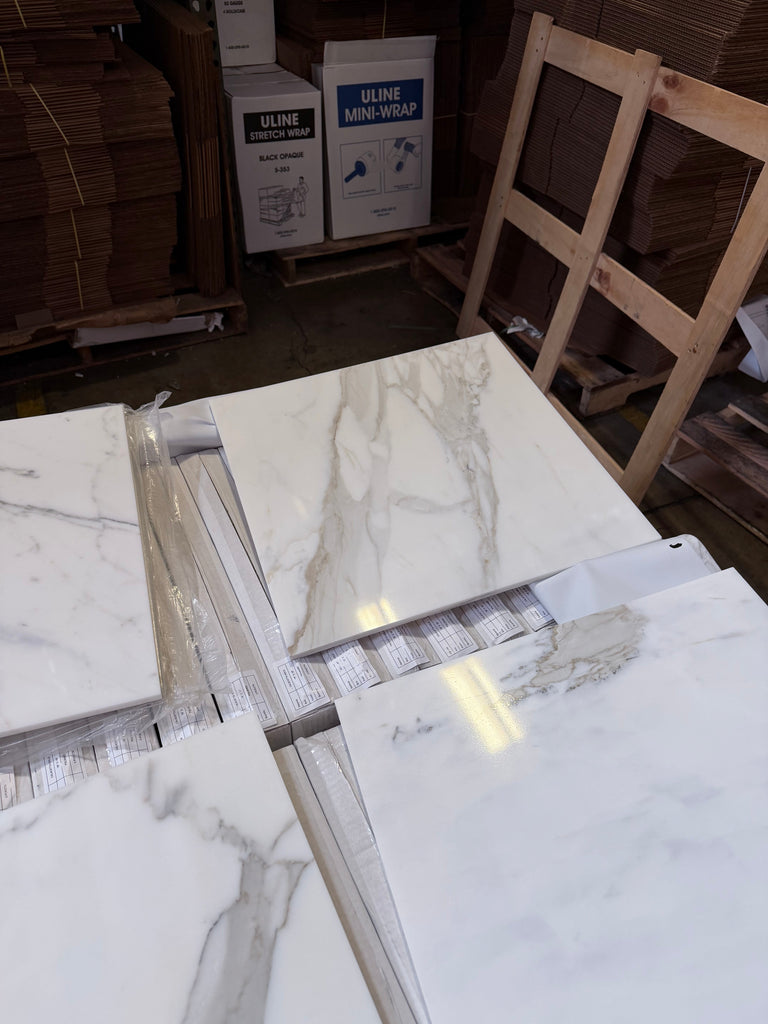 Calacatta Gold Marble 18x18 polished tiles stacked on warehouse floor