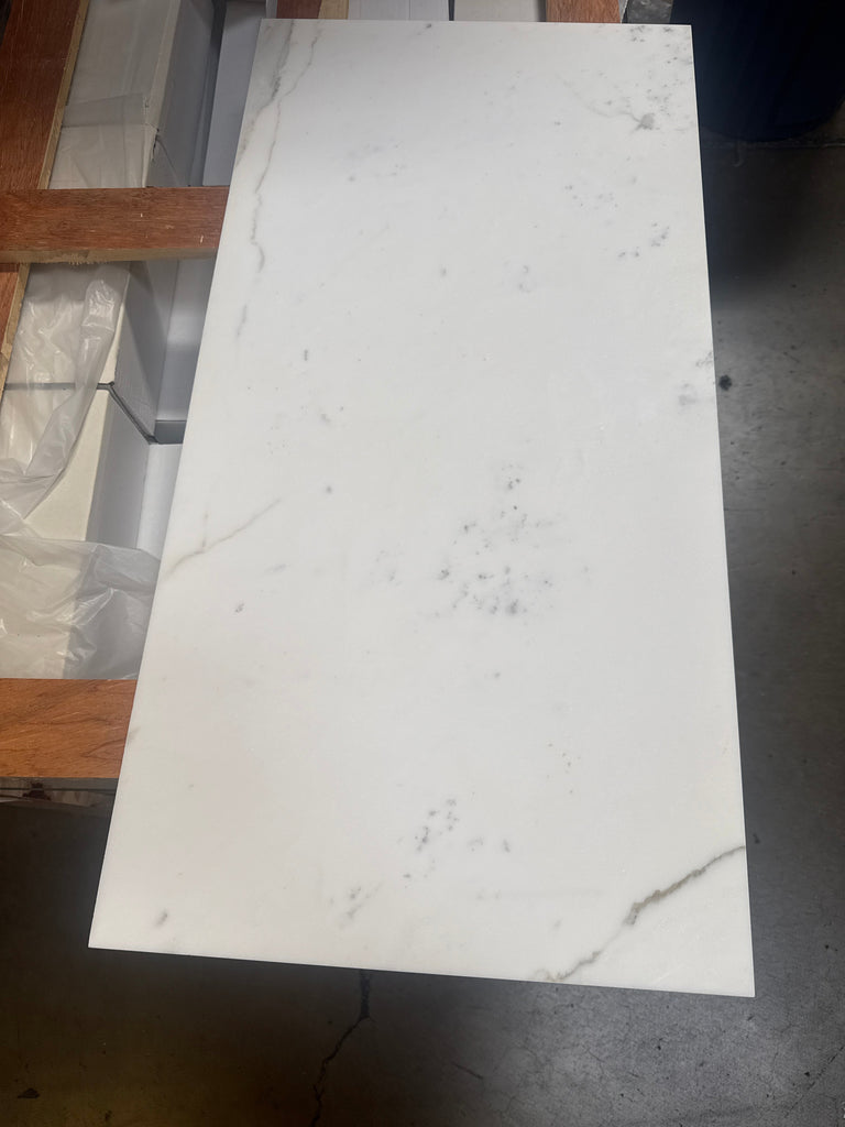 White Calacatta Gold Marble slab with subtle grey veining and darker smudges