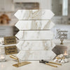 Stack of calacatta gold marble 3 x 12 inch picket mosaic hexagonal tiles in white and beige with natural veining