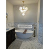 White freestanding bathtub with brown wooden bath mat placed over calacatta gold marble 3x6 polished or honed tiles