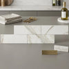 White rectangular calacatta gold marble 4x12 polished tiles with gray veining in a modern kitchen setting