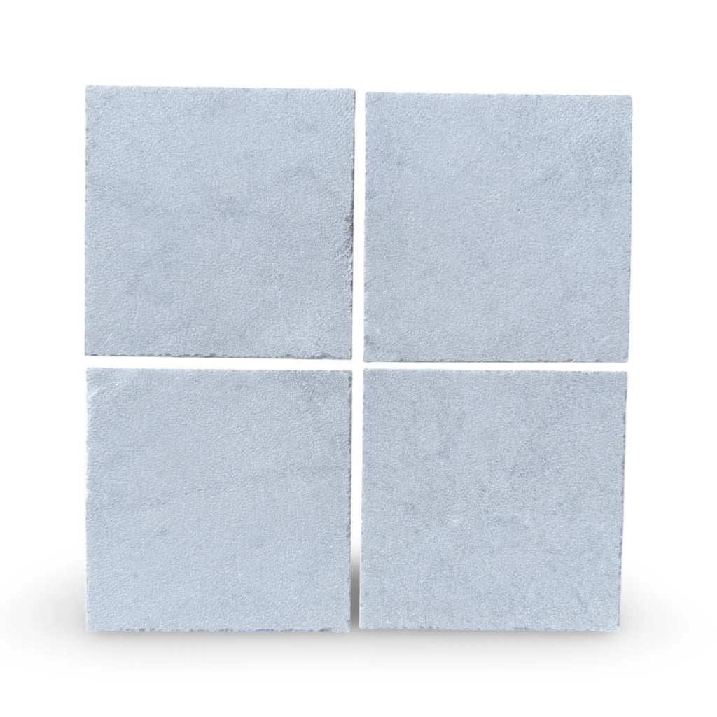 Four square concrete pavers in Calacatta Gold Marble with a sand blasted finish