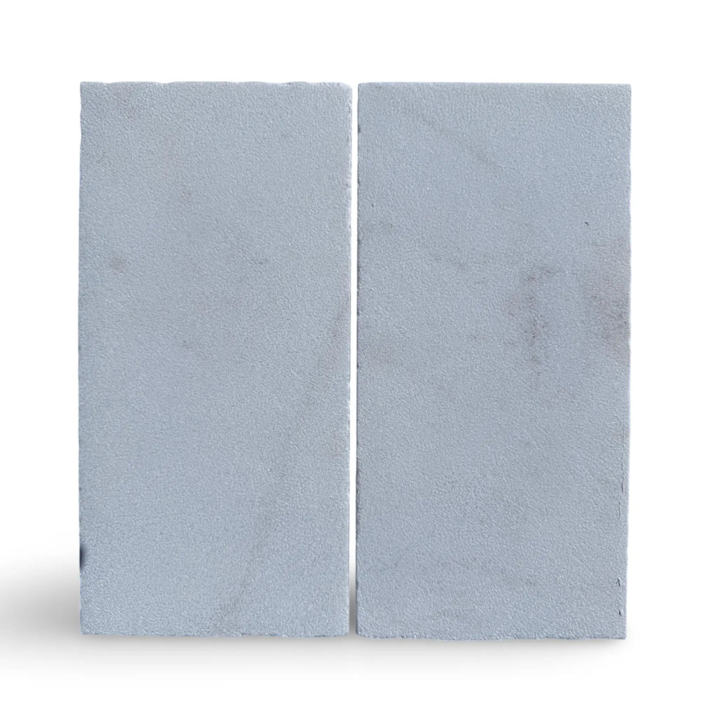 Two gray concrete blocks displayed with Calacatta Gold Marble in a sand blasted finish