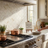 A stack of white ceramic plates with subtle texture on a marble countertop featuring calacatta gold stanza mosaic tile