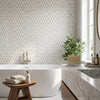 White freestanding bathtub with sleek modern design and smooth glossy finish paired with calacatta gold triangular hexagon mosaic marble tile tumbled
