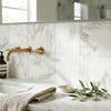 Gold-toned wall-mounted faucet with sleek modern design installed above calacatta verde royale marble 12x12 polished tile
