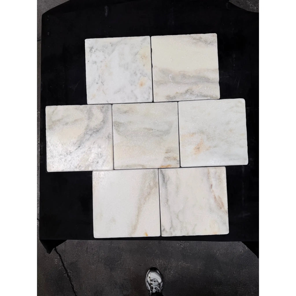 Six square white calacatta verde royale marble 12x12 tiles with subtle gray veining arranged in a cross pattern